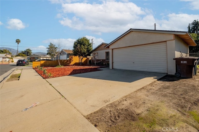 view of side of property featuring a garage, a residential view, and stucco siding