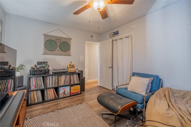 living area with light wood-type flooring, visible vents, and ceiling fan