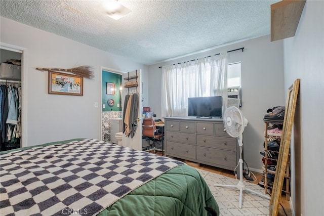 bedroom featuring light wood finished floors, a textured ceiling, a closet, and ensuite bathroom