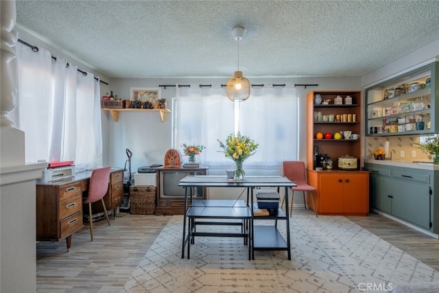 dining area featuring light wood-style floors and a textured ceiling