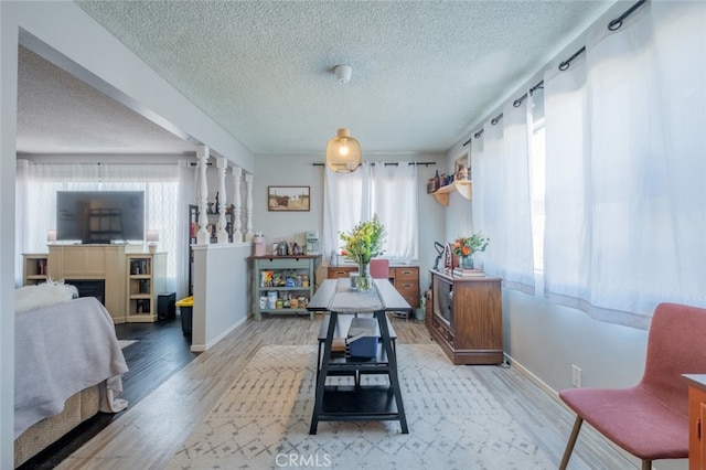 dining room featuring a textured ceiling, a fireplace, baseboards, and wood finished floors