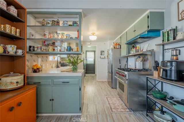 kitchen featuring stainless steel stove, a sink, light countertops, light wood-type flooring, and open shelves