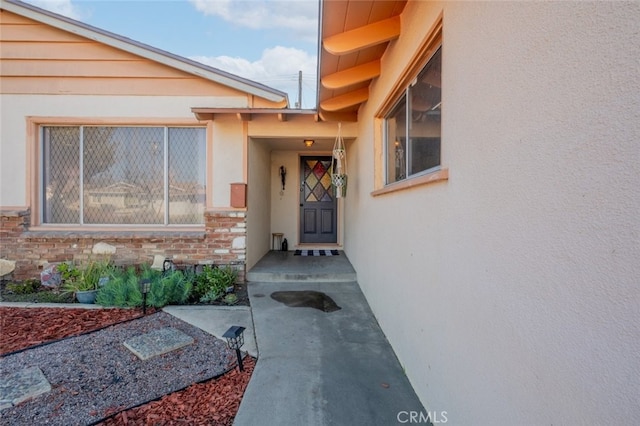 view of exterior entry with stone siding and stucco siding