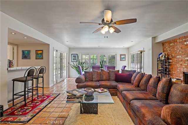 living room featuring french doors, a fireplace, light tile patterned floors, ceiling fan, and baseboards