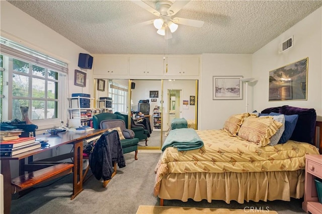 bedroom featuring a closet, light colored carpet, visible vents, a ceiling fan, and a textured ceiling