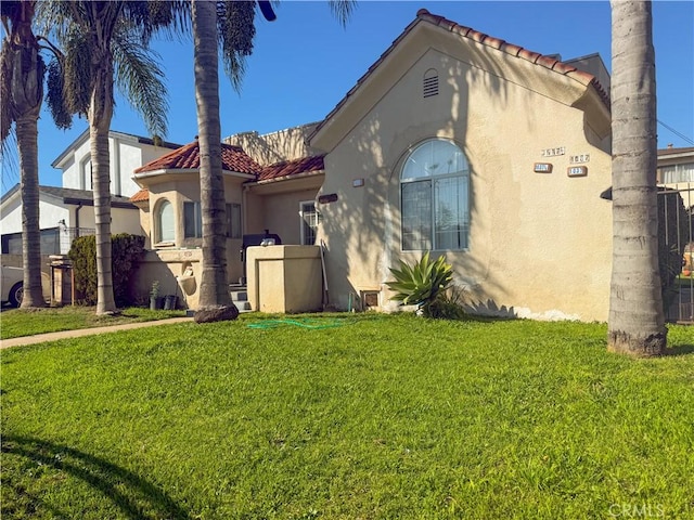 view of home's exterior with a tile roof, a yard, and stucco siding