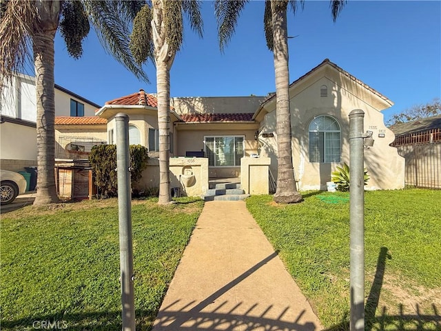 mediterranean / spanish-style home featuring a front lawn, fence, a tile roof, and stucco siding