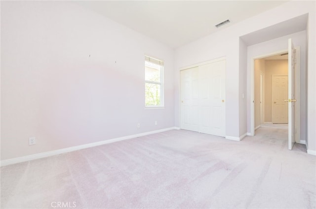 unfurnished bedroom featuring light carpet, a closet, visible vents, and baseboards