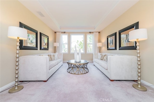 living area with light carpet, crown molding, a raised ceiling, and baseboards