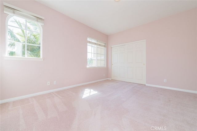 unfurnished bedroom with baseboards, a closet, and light colored carpet