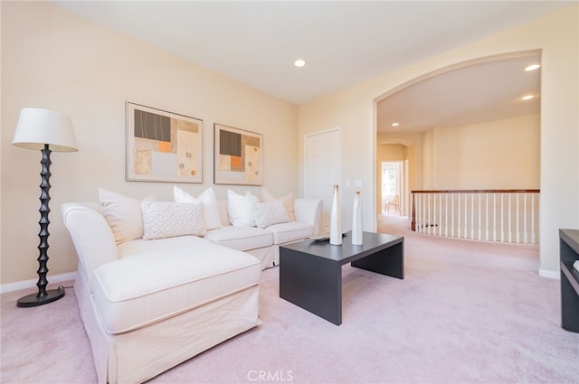 carpeted living area featuring baseboards, arched walkways, and recessed lighting