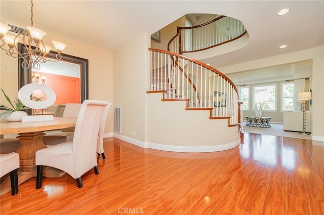 dining area with stairs, visible vents, a notable chandelier, and wood finished floors