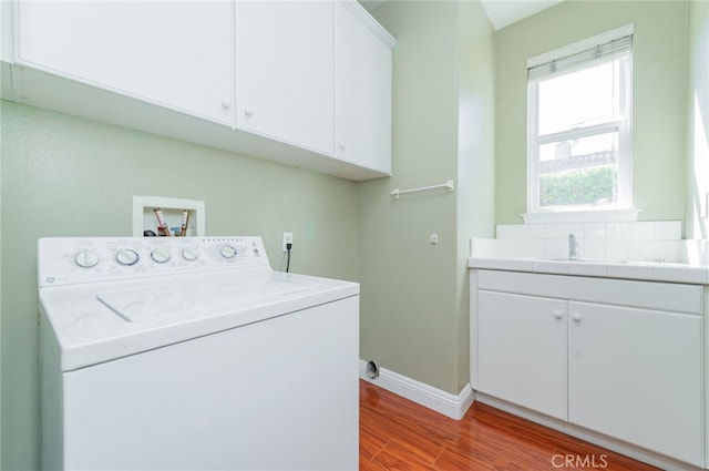 clothes washing area with light wood finished floors, cabinet space, washer / dryer, and baseboards