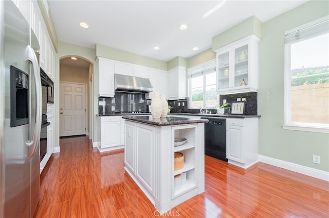 kitchen with a center island, open shelves, glass insert cabinets, under cabinet range hood, and black appliances