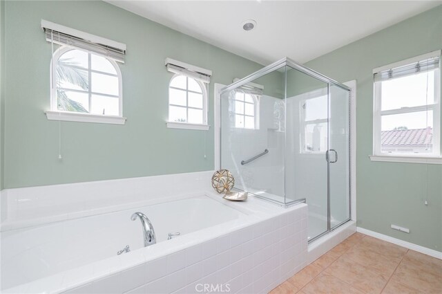 full bath featuring a stall shower, tile patterned flooring, baseboards, and a bath