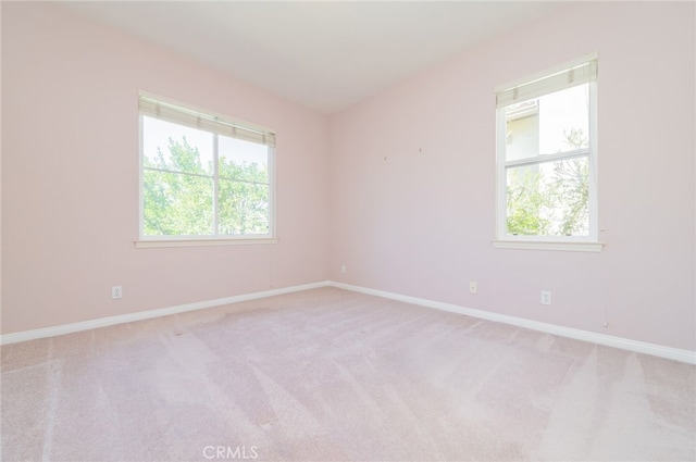 empty room with plenty of natural light, baseboards, and light colored carpet