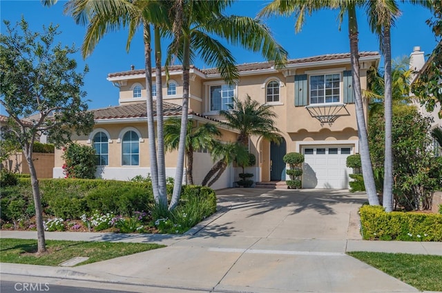 mediterranean / spanish-style home with concrete driveway, an attached garage, a tile roof, and stucco siding