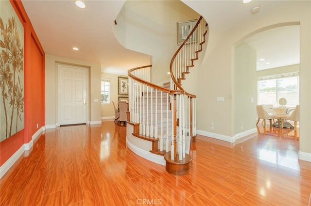 entrance foyer featuring stairs, arched walkways, wood finished floors, and recessed lighting