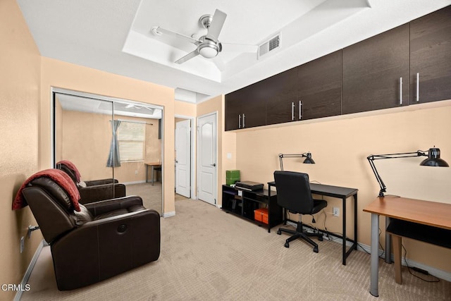 office area featuring light carpet, visible vents, a raised ceiling, baseboards, and ceiling fan