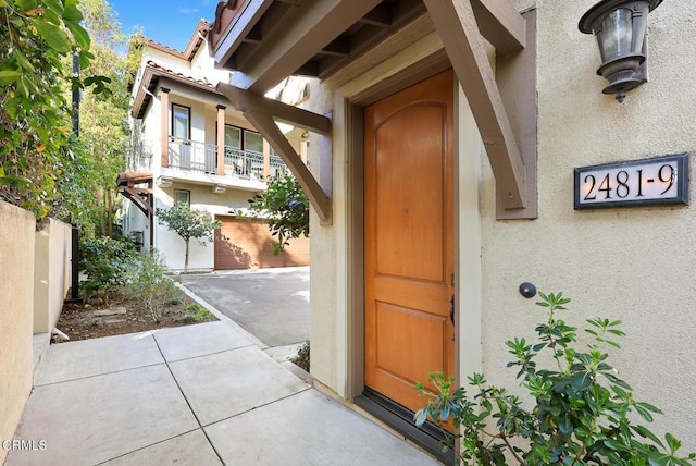 view of exterior entry featuring a patio, fence, and stucco siding