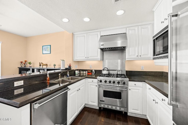 kitchen with white cabinets, wall chimney range hood, a peninsula, and high quality appliances