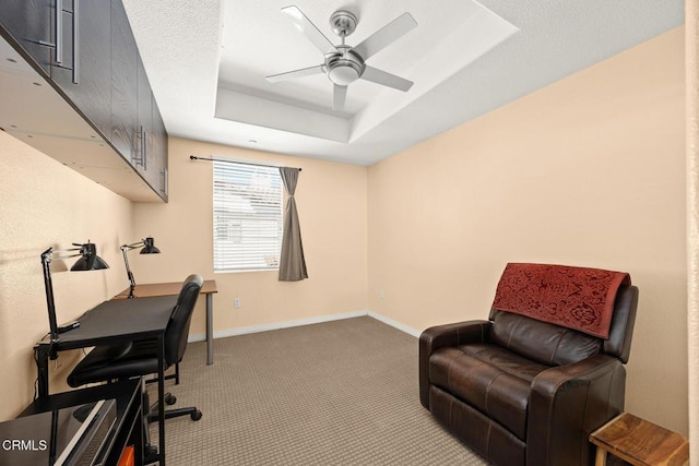 home office with carpet floors, a tray ceiling, baseboards, and a ceiling fan