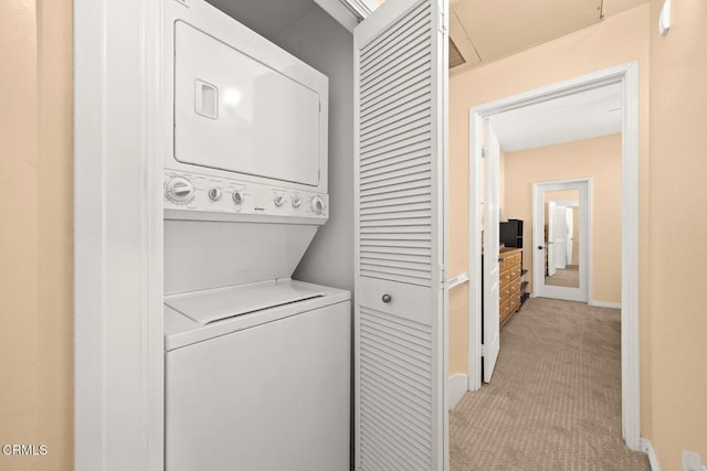 laundry room with light carpet, laundry area, stacked washing maching and dryer, and baseboards