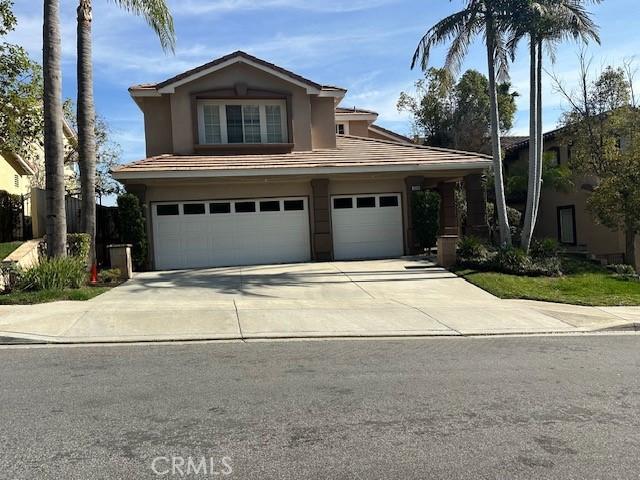 view of front of home featuring driveway, a tiled roof, an attached garage, and stucco siding