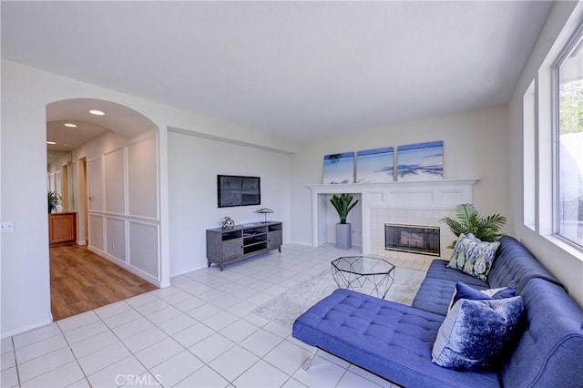 living area featuring arched walkways, light tile patterned flooring, a fireplace, and recessed lighting