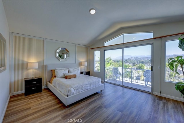 bedroom featuring access to exterior, lofted ceiling, multiple windows, and wood finished floors