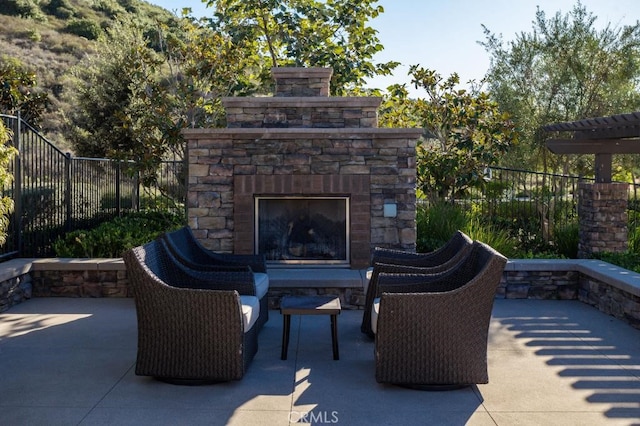 view of patio with an outdoor stone fireplace and fence