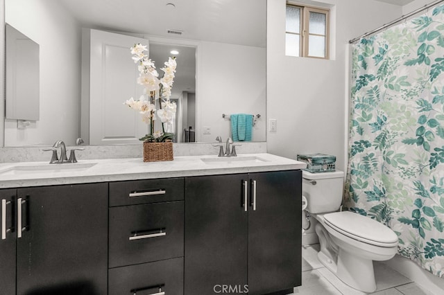 full bath featuring double vanity, a sink, toilet, and tile patterned floors