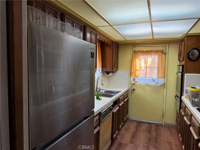 kitchen featuring tasteful backsplash, appliances with stainless steel finishes, dark wood-type flooring, light countertops, and a sink