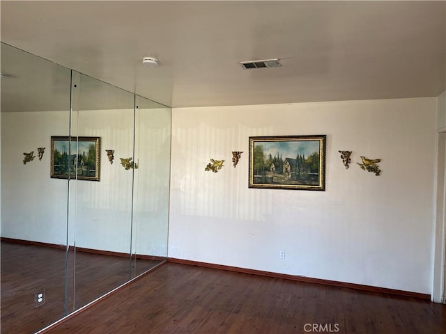 unfurnished bedroom featuring dark wood finished floors, visible vents, and baseboards