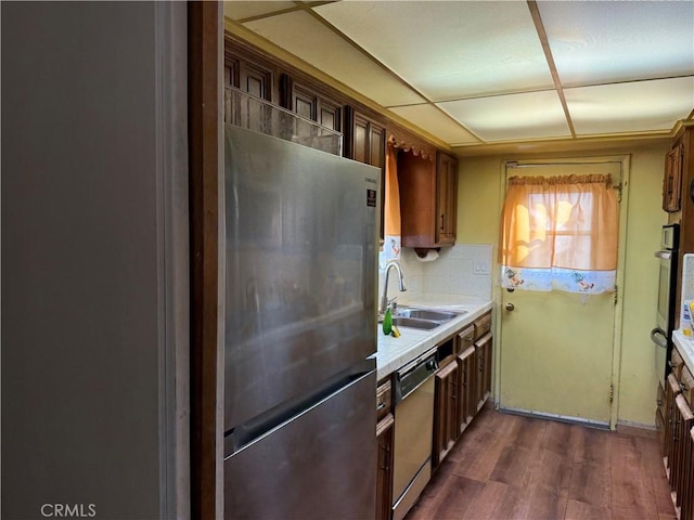 kitchen with decorative backsplash, appliances with stainless steel finishes, dark wood-type flooring, light countertops, and a sink