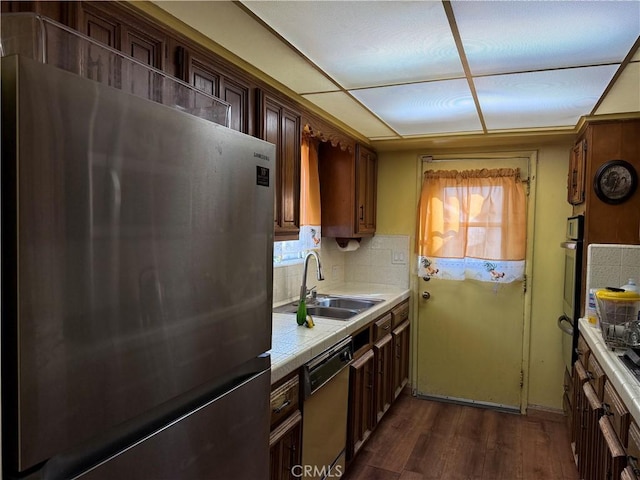 kitchen featuring dark wood-style flooring, a sink, a healthy amount of sunlight, appliances with stainless steel finishes, and backsplash