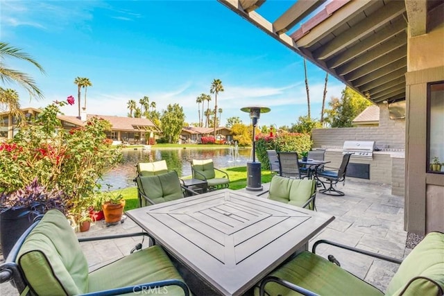 view of patio / terrace with exterior kitchen, outdoor dining space, a water view, and area for grilling