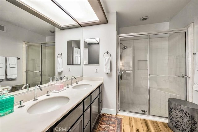 bathroom with a stall shower, a sink, and wood finished floors