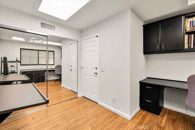 office space with a ceiling fan, light wood-type flooring, visible vents, and baseboards