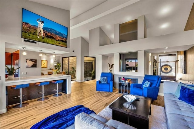 living room with a towering ceiling, baseboards, and wood finished floors