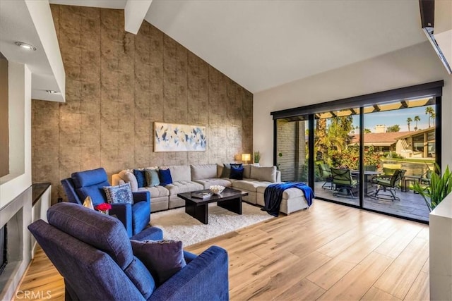 living area featuring high vaulted ceiling, beamed ceiling, and wood finished floors