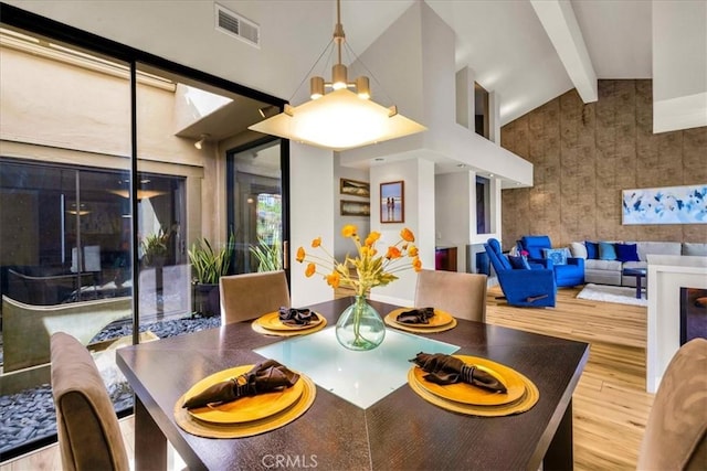 dining area with beam ceiling, visible vents, an inviting chandelier, wood finished floors, and high vaulted ceiling