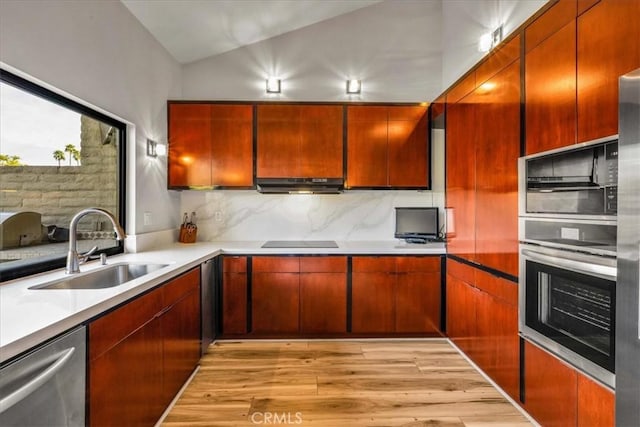 kitchen with stainless steel appliances, backsplash, a sink, light wood-type flooring, and under cabinet range hood