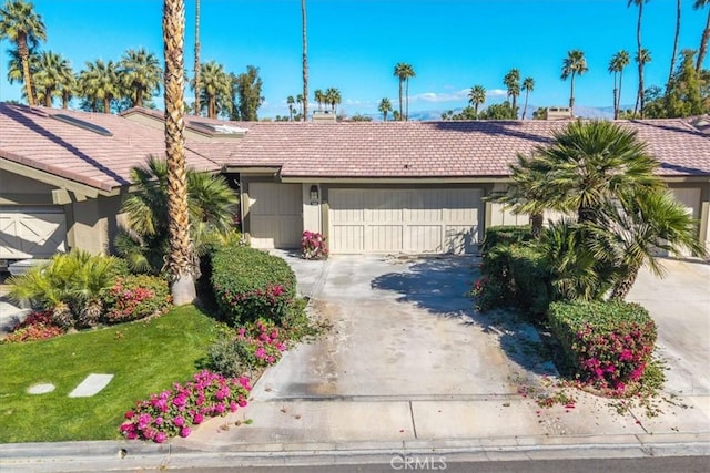 view of front of home with a garage, a tiled roof, and concrete driveway