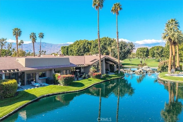 view of pool with a lawn, a patio area, and a water and mountain view