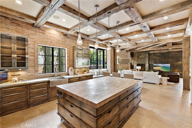 kitchen featuring brick wall, butcher block counters, coffered ceiling, a sink, and beam ceiling