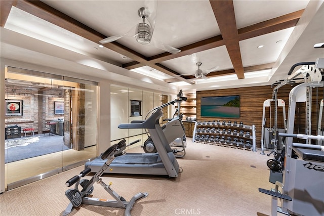 workout area featuring carpet floors, wood walls, coffered ceiling, and a ceiling fan