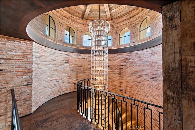 corridor featuring an upstairs landing, wood-type flooring, a high ceiling, and an inviting chandelier