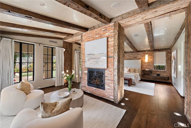 living area featuring visible vents, brick wall, hardwood / wood-style floors, a fireplace, and beam ceiling