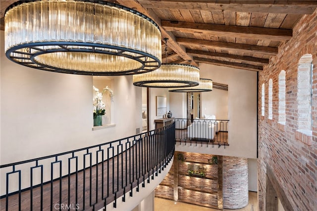 hall featuring vaulted ceiling with beams, wooden ceiling, brick wall, and an upstairs landing